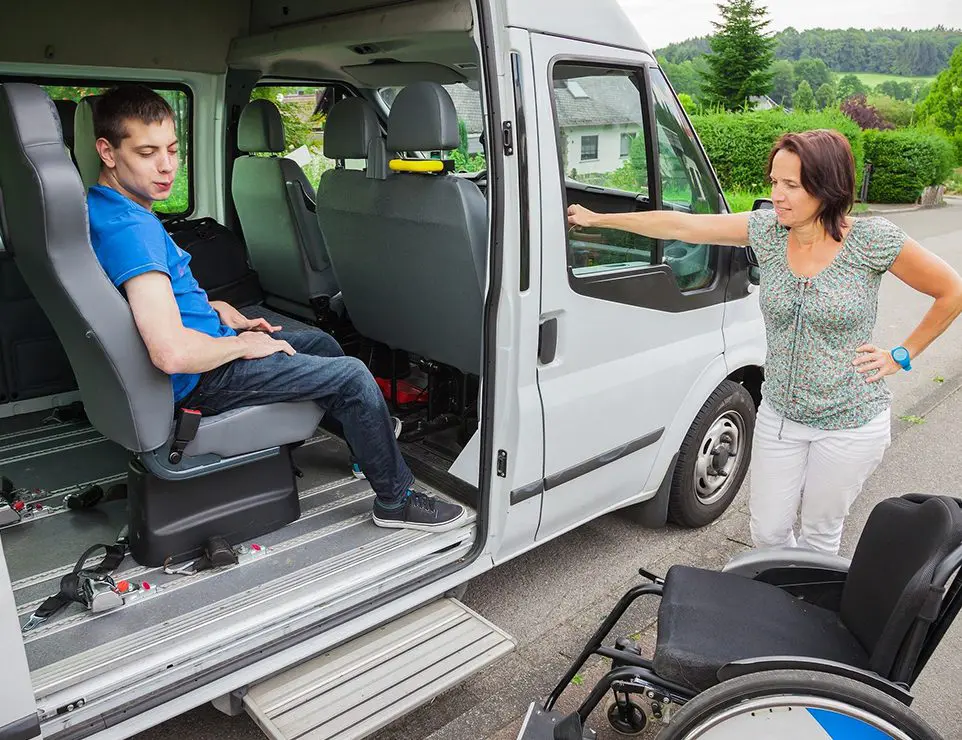 A woman in a wheelchair is standing next to a van.