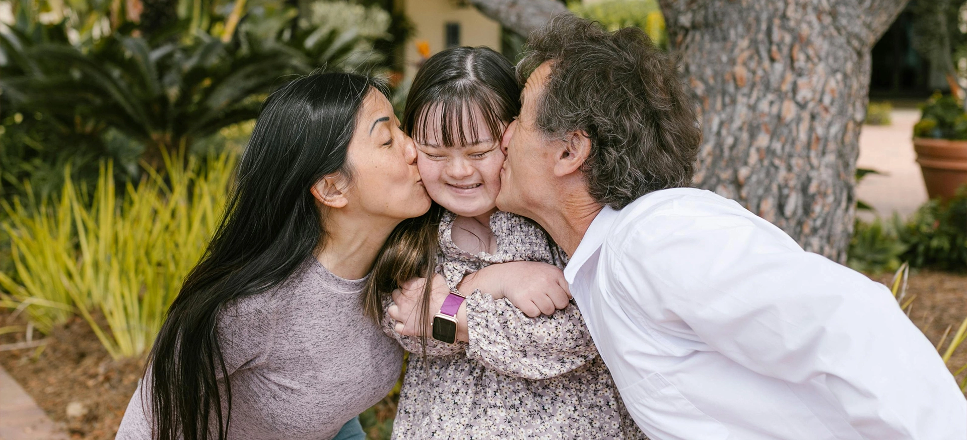 A woman and two men kissing a girl.